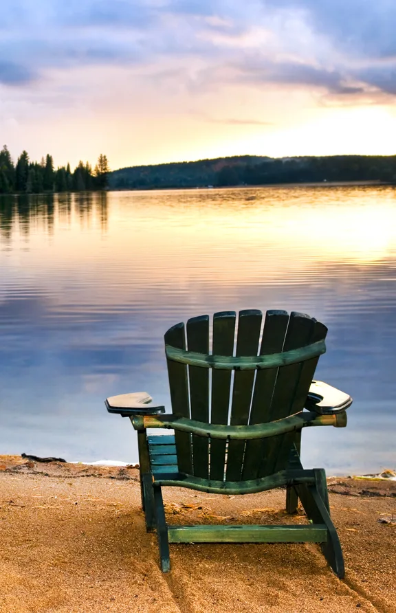 Chair on the beach looking out over the lake, sun and horizon