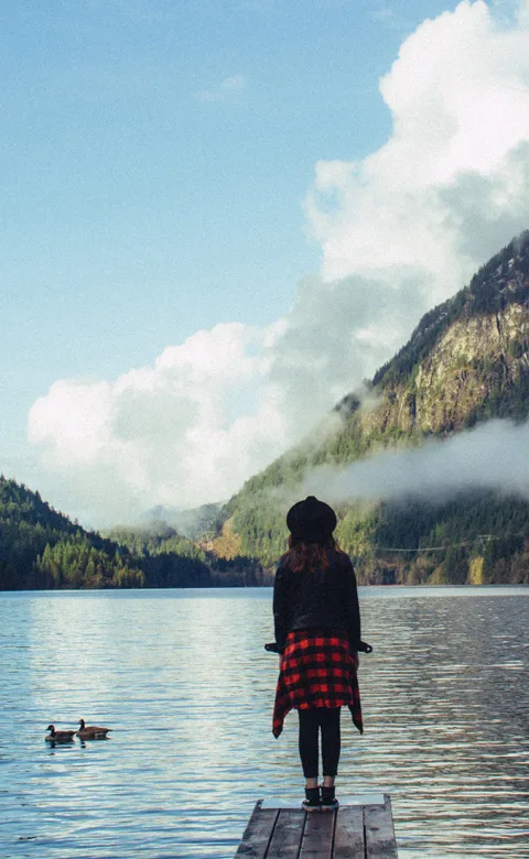 Woman on dock overlooking lae and mountains