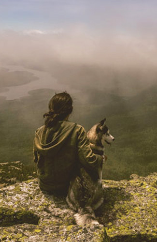 Woman with dog looking out over misty valley