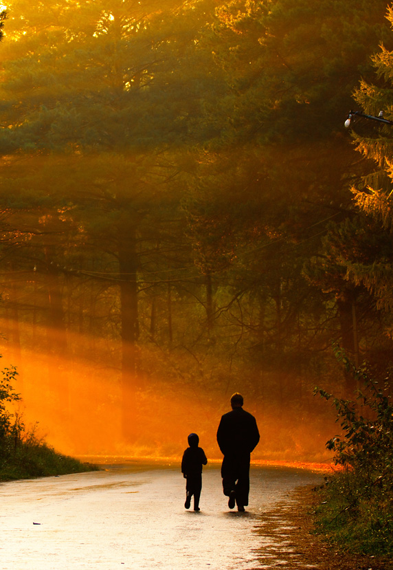 Young and older persons walking through forest